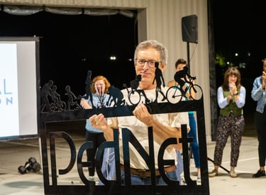 Man holding a metal "PedNet" logo sign