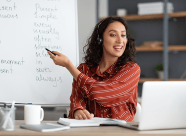 a woman in a red shirt is pointing at a white board
