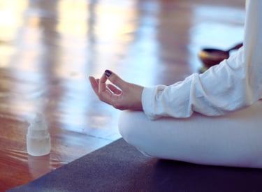 a close up of a woman's hand on a mudra position next to a selenite crystal grid