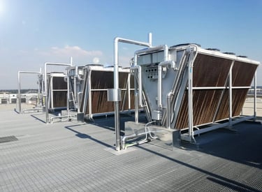 Industrial rooftop HVAC cooling towers with adiabatic pads and stainless steel piping.