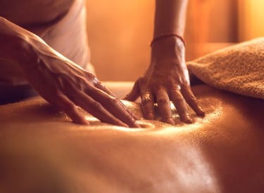 Professional massage therapist applying warm oil on client’s back during relaxing full body massage