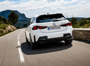BMW hatch branco visto de traseira em estrada montanhosa com visual esportivo
