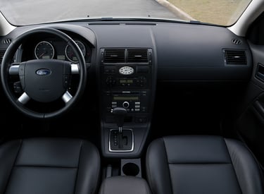 Interior do Ford Mondeo com volante, painel central e bancos em couro preto.