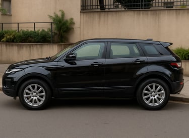 Range Rover Evoque preto visto de perfil em rua urbana, com rodas de liga leve e design elegante.