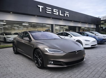 Tesla Model S estacionado em frente a concessionária Tesla com outros modelos ao fundo