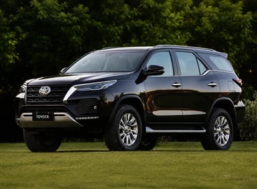 Toyota SW4 preta estacionada sobre gramado com árvores ao fundo