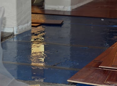 alt="Flooded floor with visible storm damage inside residential home"