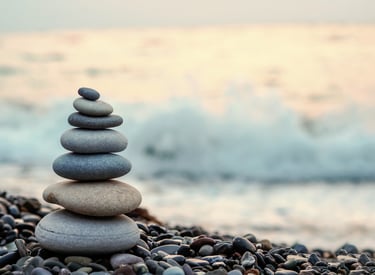 Stacked stones balanced near the ocean symbolizing peace and preparation before loss.