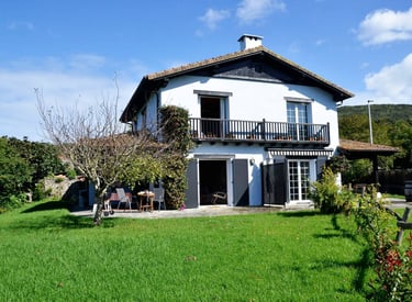 Fachada del chalet azul con un gran jardín orientado al sur