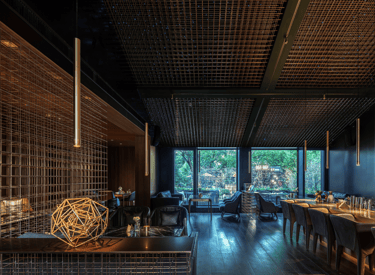 Modern luxury bar interior with industrial metal grid ceilings, ambient gold pendant lighting, and plush lounge seating.