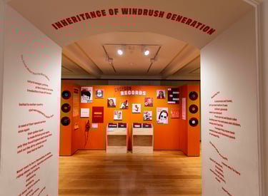an orange exhibition display of portraits and text, bordered by a white wall with orange text