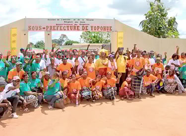 Community group in orange and green shirts posing at Sous-Prefecture de Yopohue in Gagnoa, Ivory Coast.