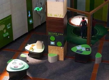 A modern exhibition space featuring interactive displays and informational panels predominantly in g