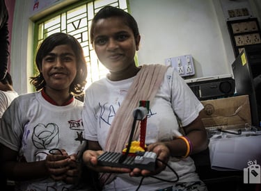 Two students in India proudly display a LEGO WeDo 1.0 robot they programmed, showcasing STEM skills.