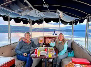 two women sitting at a table with drinks on a sunset eco-friendly electric boat cruise