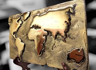Handcrafted bronze world map plaque on a display stand with a textured metallic finish.