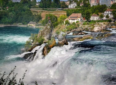 A waterfall in the middle of a river with a view of a city, accessible with our private driver