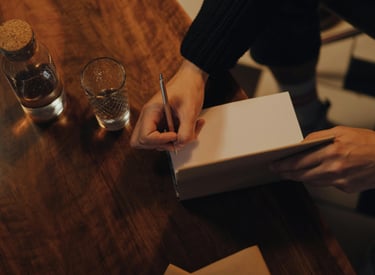A picture of a man's hand preparing to sign the inside of a novel