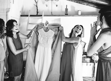 La sposa e la damigella d'onore preparano divertite l'abito da sposa