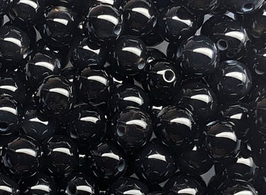 Perles en onyx noir, d’un noir intense avec une finition lisse et brillante, reflétant la lumière