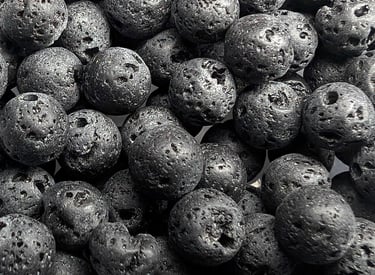Perles en pierre de lave noire, à la texture poreuse et rugueuse, offrant un aspect brut et naturel