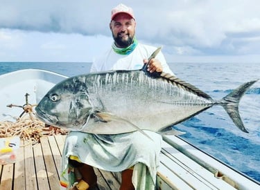 Angler holding a massive Giant Trevally on a Zanzibar fishing charter, perfect for deep-sea fishing 