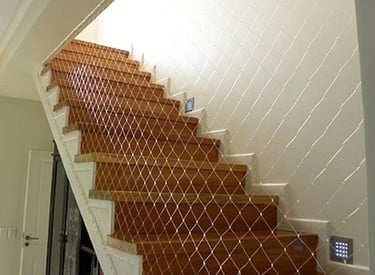 Safety netting installed along a staircase railing to prevent falls.