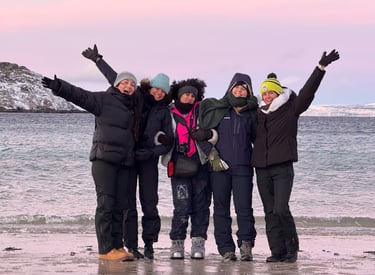 a group of people standing on a beach dressed in winter gear with fun poses and happy faces 