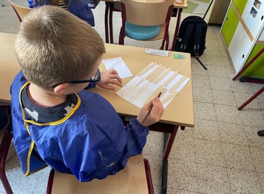 Image d'un élève en activité individuelle qui peint des bâtonnets de bois