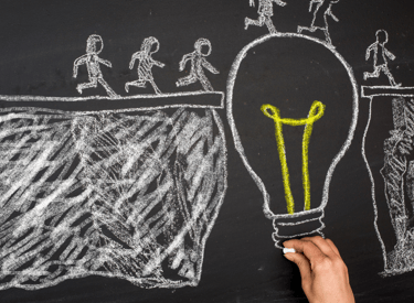 a person holding a light bulb in front of a chalkboard