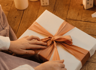 a person holding a present box with a bow
