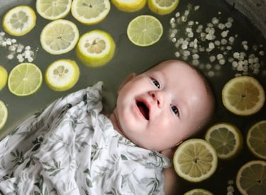 bain de lait bebe avec bebe entouré de citron et de fleurs ou d'autres fruits