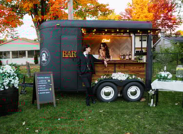 a bride and groom standing in front of our mobile trailer bar