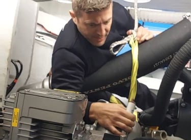 Técnico náutico reparando el motor de una embarcación en un taller especializado en Menorca, con her