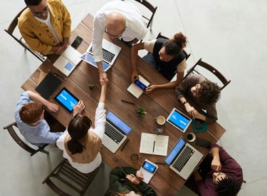 a group of people sitting around a table with laptops