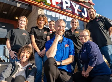 a group of people standing in front of a happy j j's restaurant