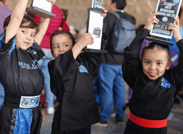 niños levantando trofeos después de torneo de prekarate