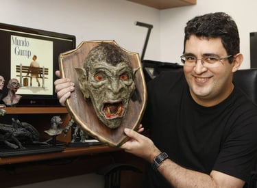 Philipe Kling David segura uma cabeça de Orc decepada enquanto posa na frente do computador