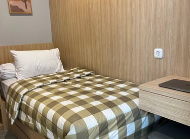 Kamar kos eksklusif Kos Si Bos Surabaya dengan single bed, meja belajar, lemari kayu, dan suasana modern minimalis