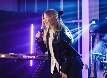 a woman in a black suit singing on the stage