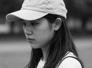A single sneaker resting against a rough-textured concrete surface with a slight green tint. The shoe is dark with a prominent rubber sole and features several stripes along the side.