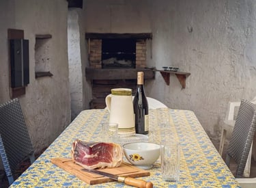 Une table d'extérieur avec une bouteille de vin et un morceau de jambon