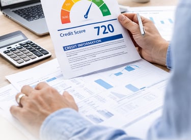 A person reviewing a 720 credit score report at a desk with a laptop and calculator.