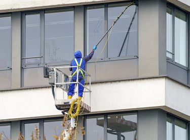 Un laveur de vitres, utilise une perche à eau pure pour nettoyer les menuiseries extérieur