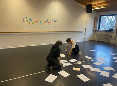 Due persone inginocchiate tra fogli e post-it colorati in uno studio luminoso