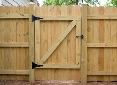 New pressure treated wood privacy fence with a matching garden gate and black metal hardware.