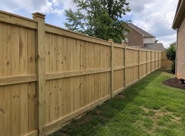 A pressure treated wood privacy fence installed along a backyard property line.