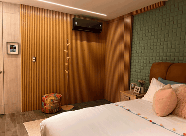Recámara con cabecera de terciopelo color miel, muro verde acolchado y detalles en madera | KARÄNA.