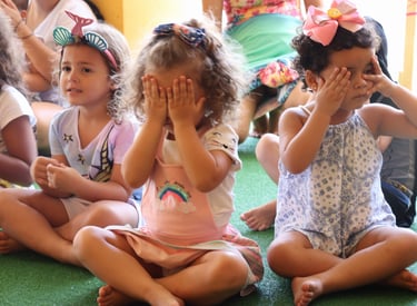 um grupo de crianças sentadas no chão em frente a um grupo de adultos