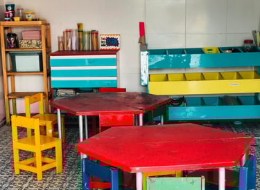 Mesinhas e bancos coloridos em uma sala de artes infantil